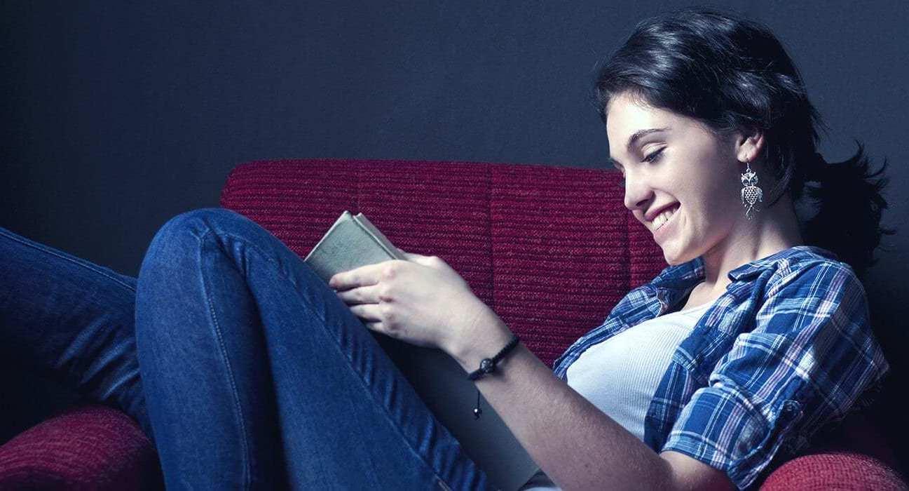 photo of a student reclining on a sofa and reading a book in campus housing and dorms at Nossi College of Art and Design in Nashville, TN