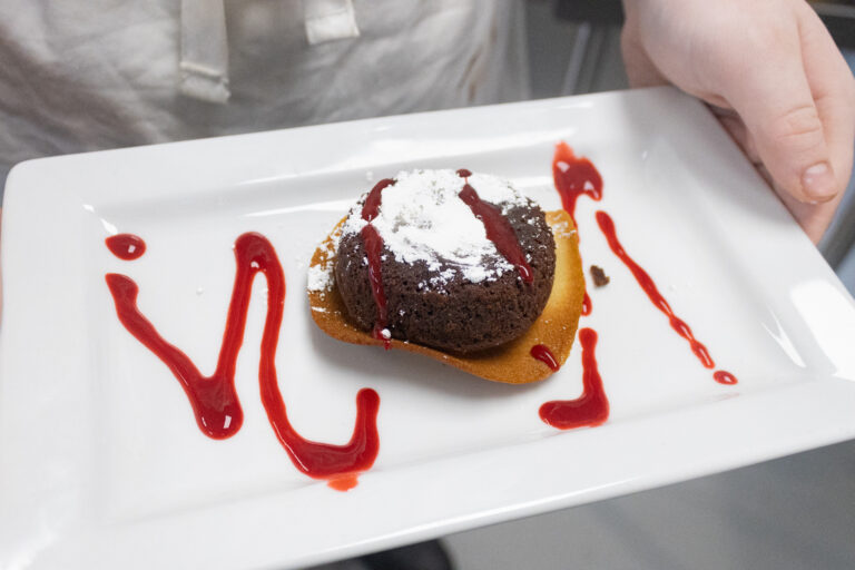 Chocolate lava cake plated with raspberry drizzle by Culinary Arts student.