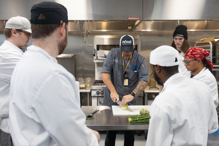 Students preparing entrées in commercial kitchen during class.
