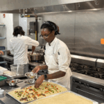68d6d2099b84da726989144f Nossi Student making pizza for class.
