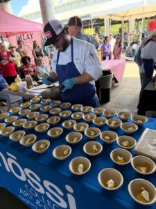 68dac5a42b345bdb180754d7 (1) Nossi Culinary student preparing samples at the Farmer's Market Cooking Demo