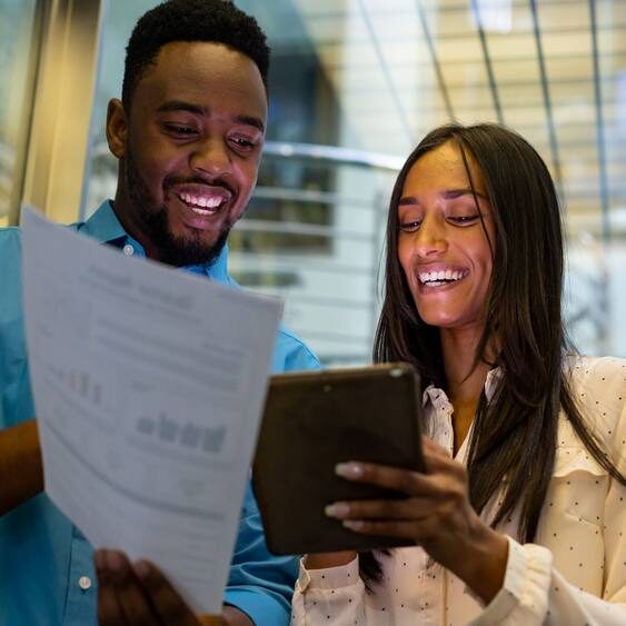 Happy multiracial colleagues discussing over document and tablet pc in elevator at modern workplace. unaltered, technology, business, teamwork and modern office concept.